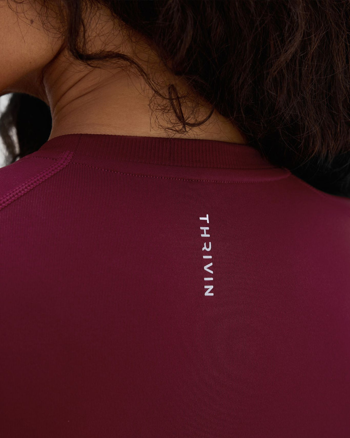 Elevate Compression T-Shirt in Fine Wine Red, back neck close-up of vertical THRIVIN logo