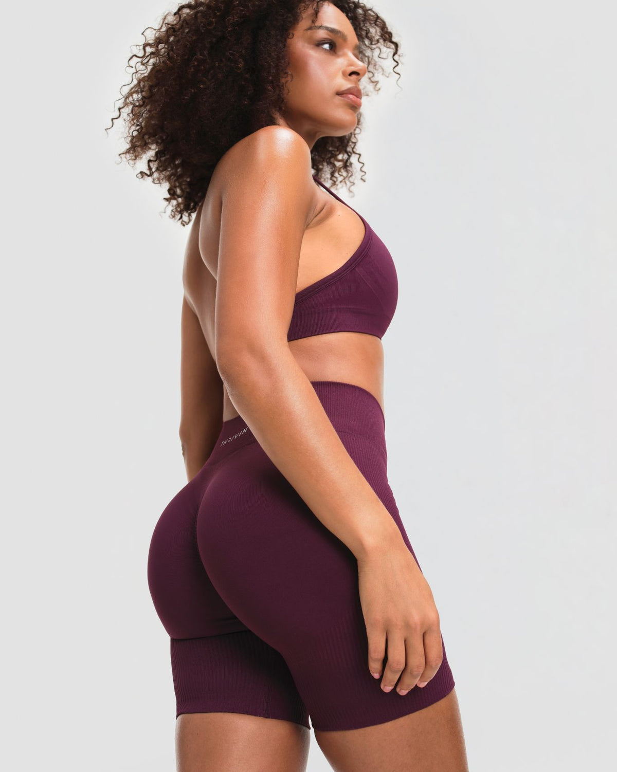 Elevate Sculpting Mid Waist Scrunch Shorts in Winter Plum Red, three-quarter back view of mid waist rise and sculpted seat