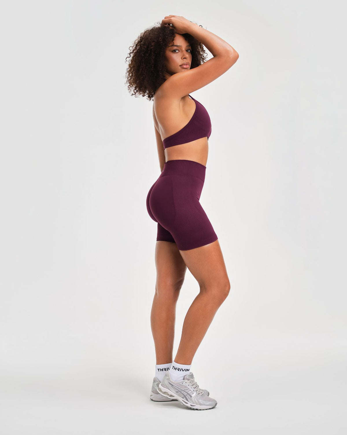 Elevate Sculpting Seamless Adjustable Halter Bra in Winter Plum Red, three-quarter back view with open back and shorts