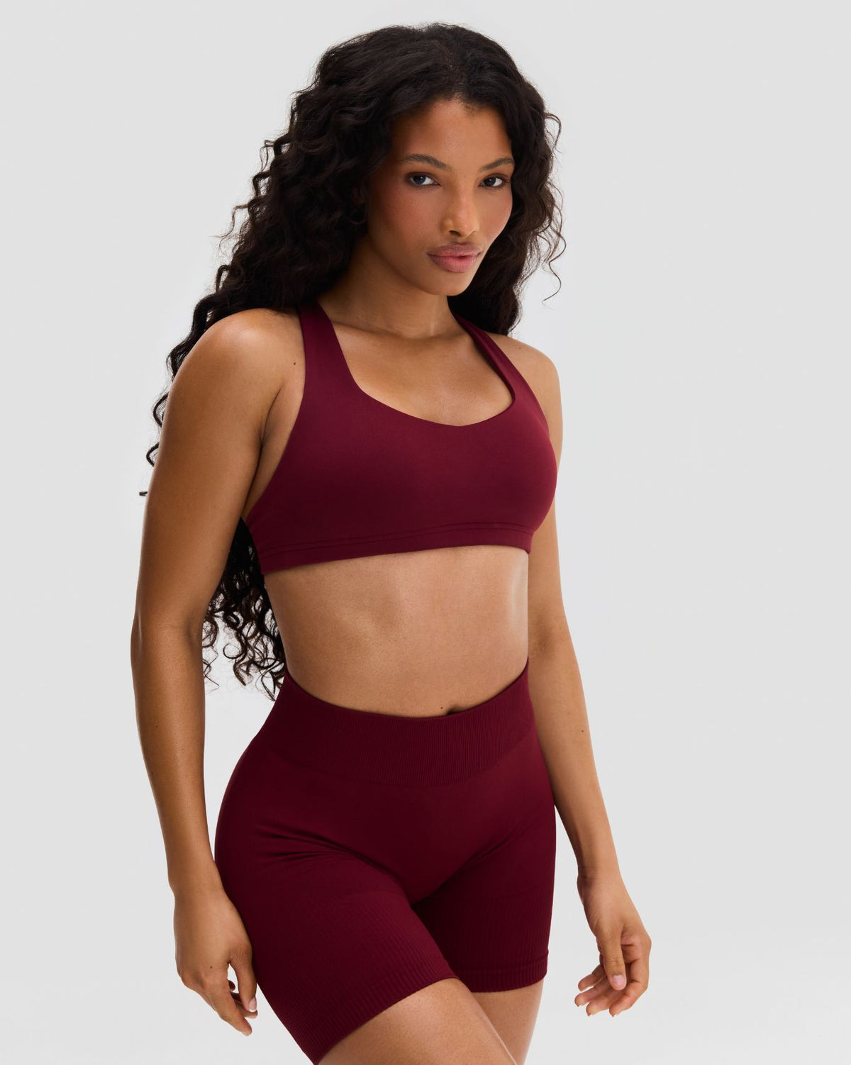 Elevate Sculpting Medium Impact Multiway Bra in Fine Wine Red, front view of bra with matching shorts, hands on hips