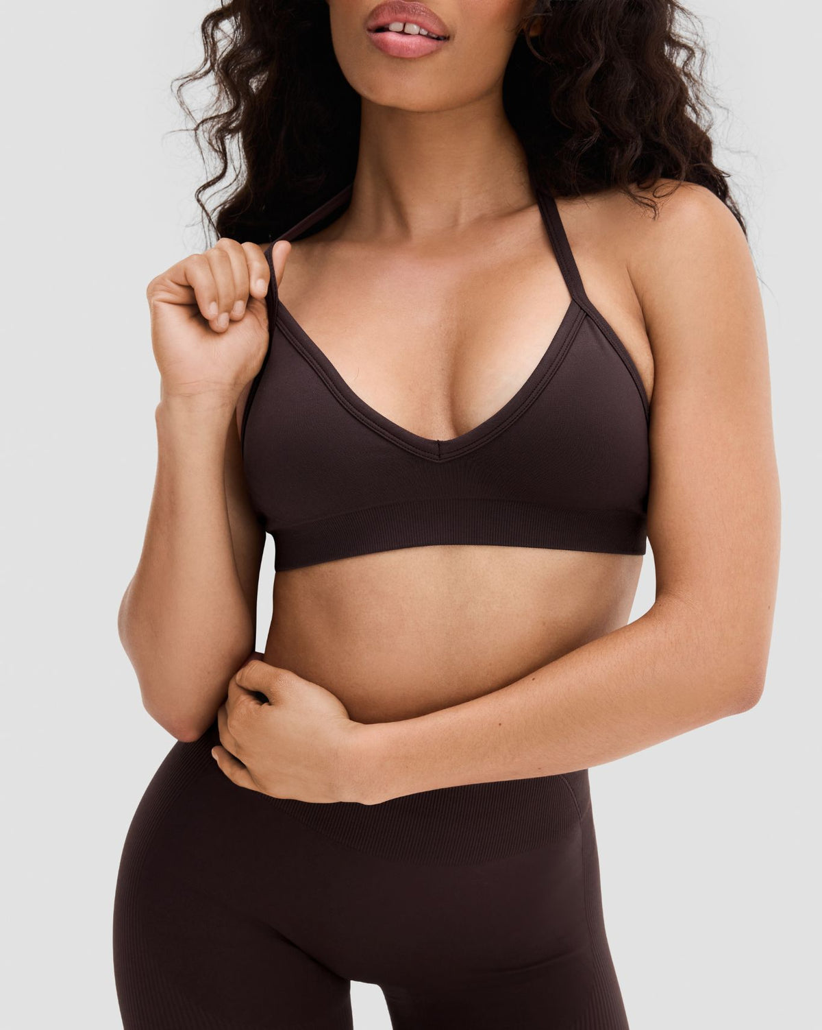 Elevate Sculpting Seamless Adjustable Halter Bra in Coffee Brown, front view with hand at chest, styled with leggings