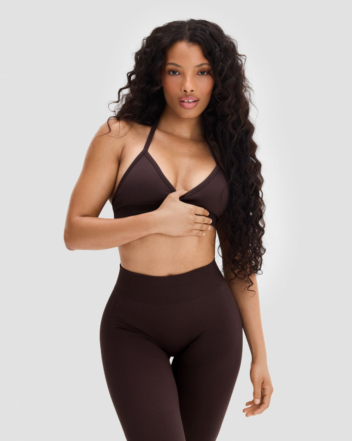 Elevate Sculpting Seamless Adjustable Halter Bra in Coffee Brown, front view with hand on stomach, halter strap