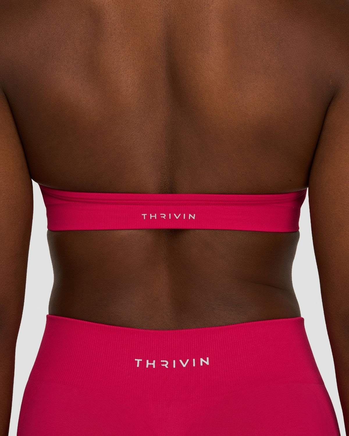 Elevate Sculpting Seamless Adjustable Halter Bra in Strawberry, back close-up of band with THRIVIN logo, with shorts