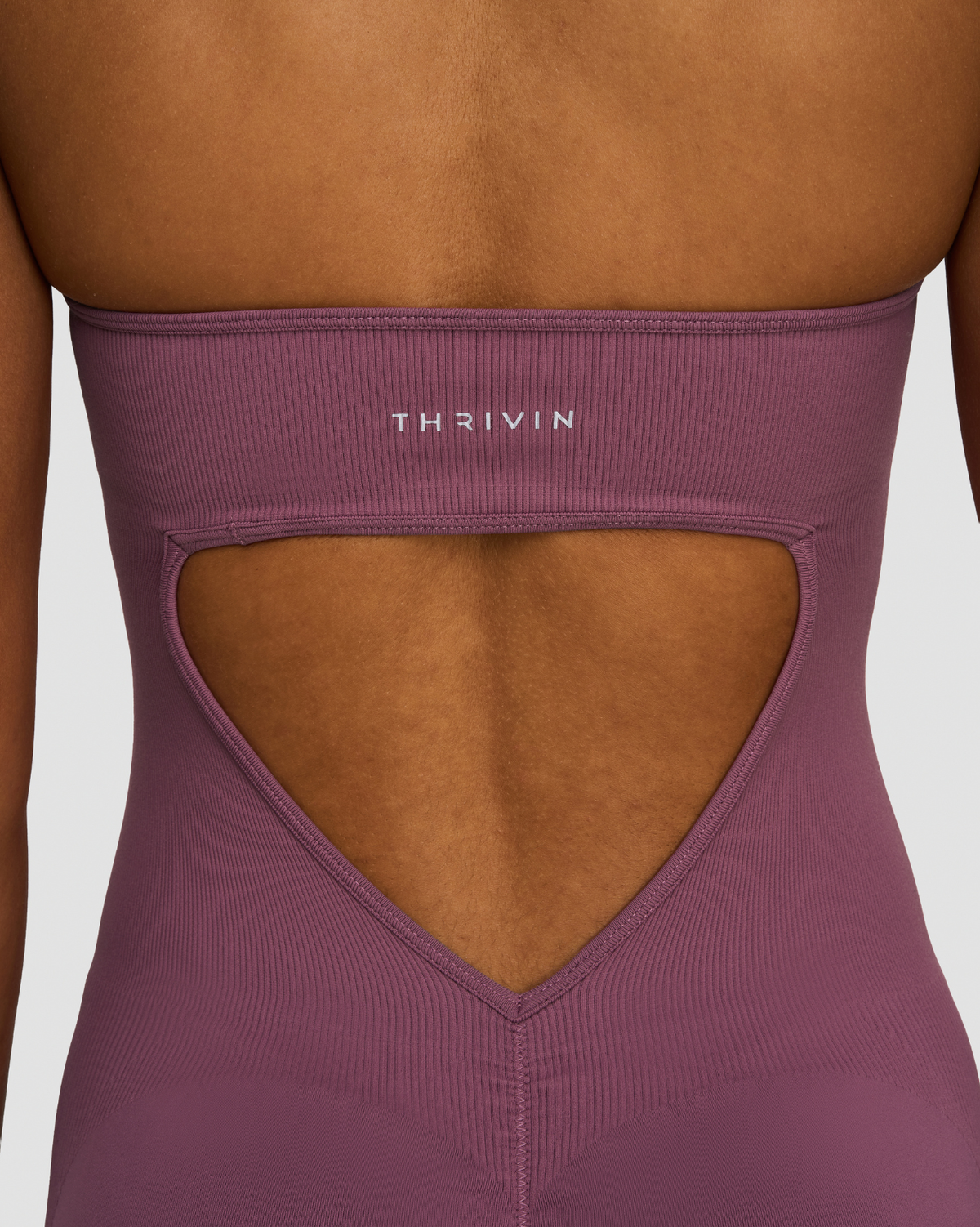 Elevate Sculpting Halterneck All In One in Orchid Mauve, back close-up of Thrivin logo, open back cutout and ribbed knit