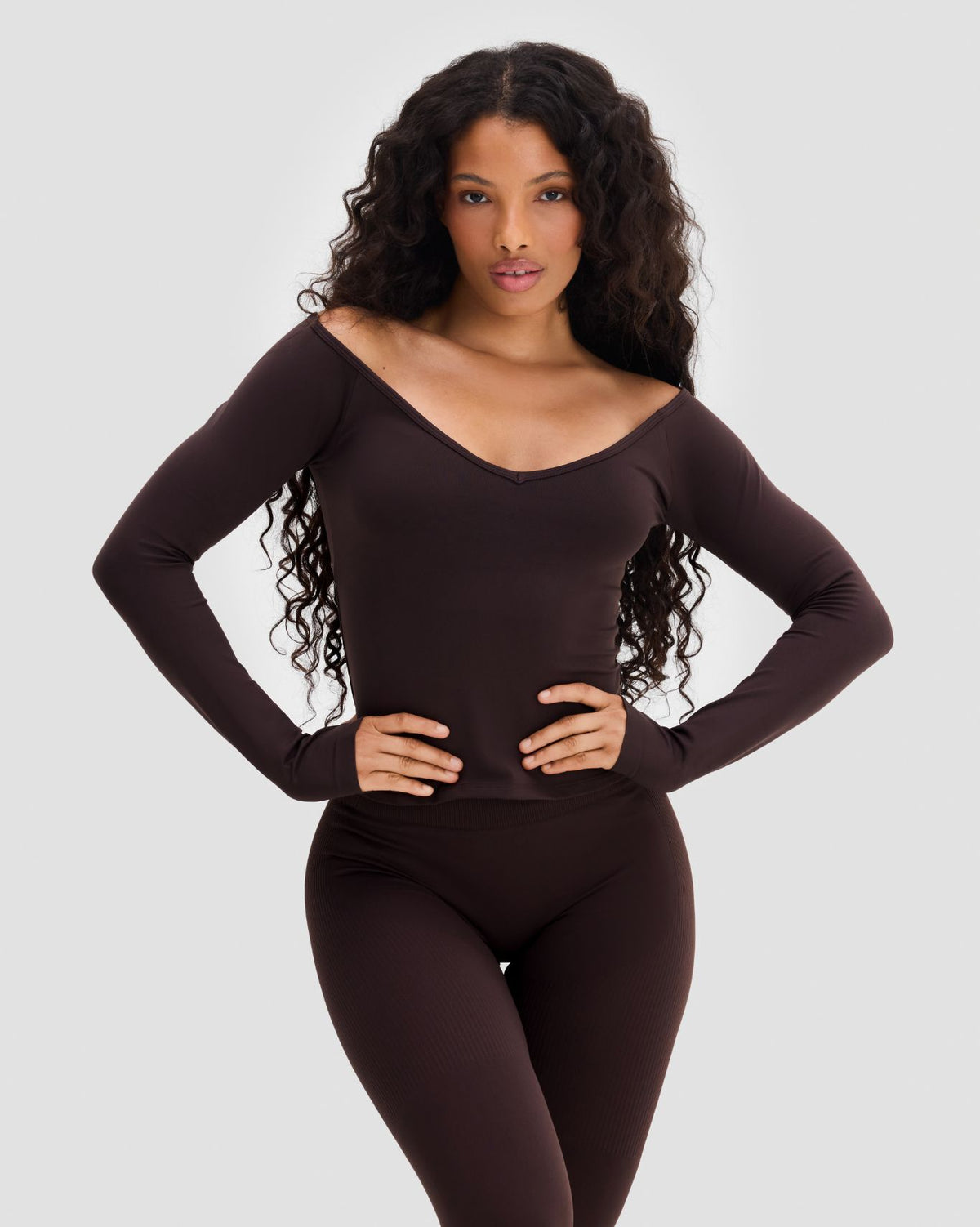 Elevate Sculpting Seamless V-Neck Top in Coffee Brown, front view with hands on hips and thumbholes