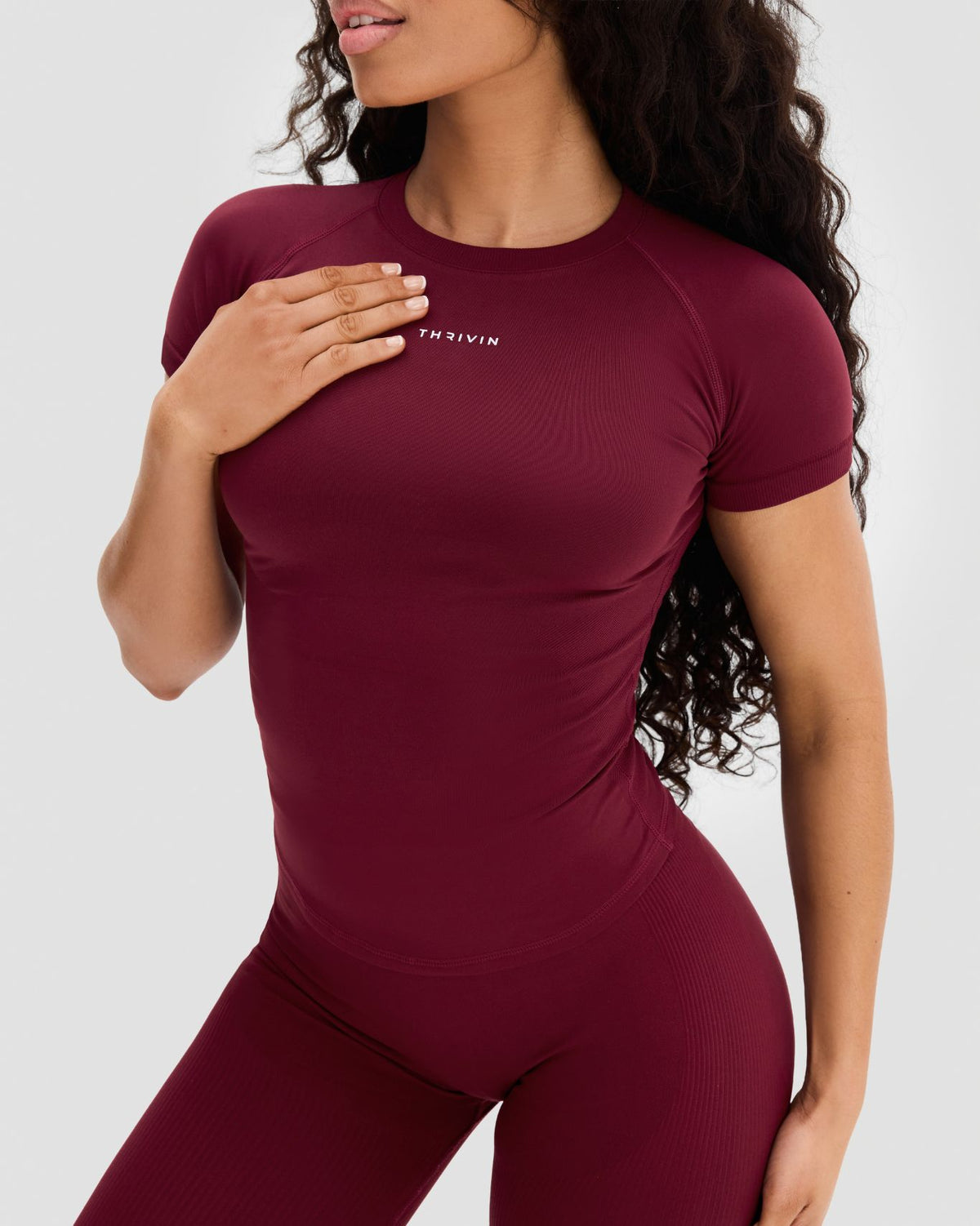 Elevate Compression T-Shirt in Fine Wine Red, front close-up with THRIVIN logo and raglan sleeves, hand on chest