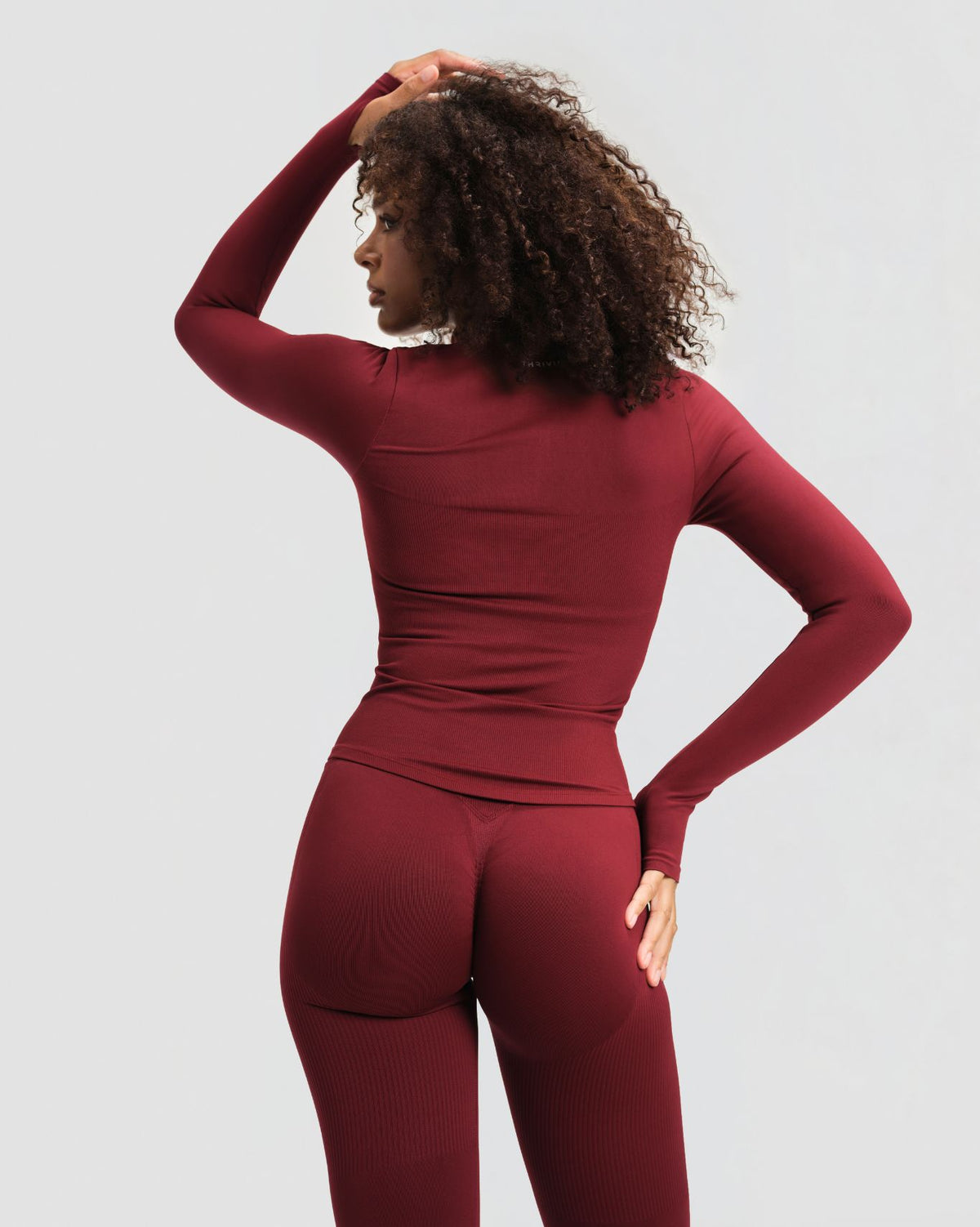 Elevate Compression Long Sleeve Jacket in Fine Wine Red, back view with fitted long sleeves, thumbholes and hip-length hem