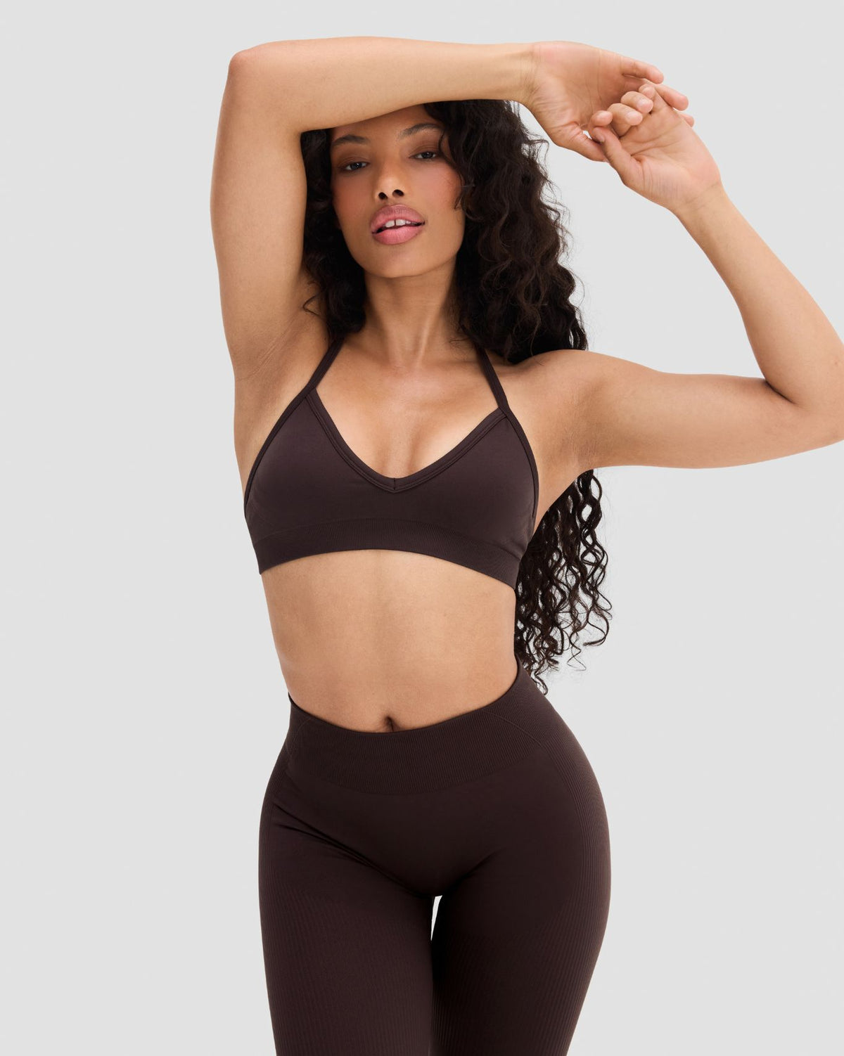 Elevate Sculpting Seamless Adjustable Halter Bra in Coffee Brown, front view with arm raised, styled with leggings