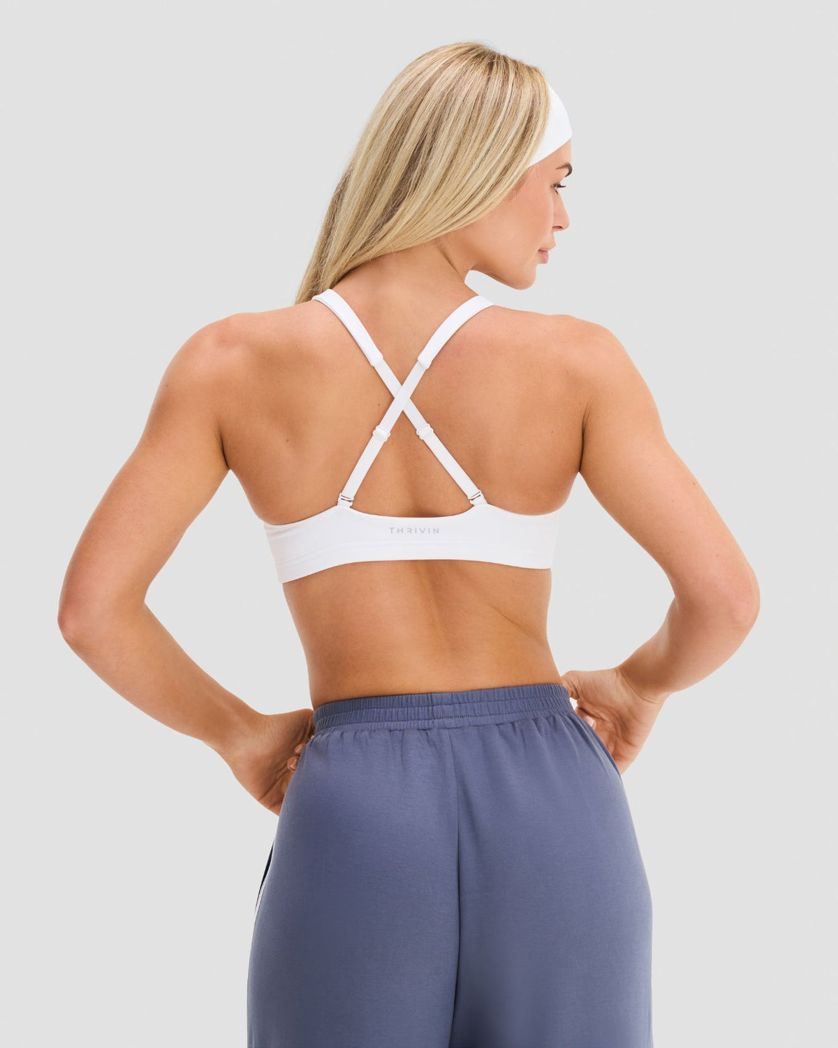 Elevate Sculpting Medium Impact Multiway Bra in White, back view with straps worn crossed and Thrivin logo underband