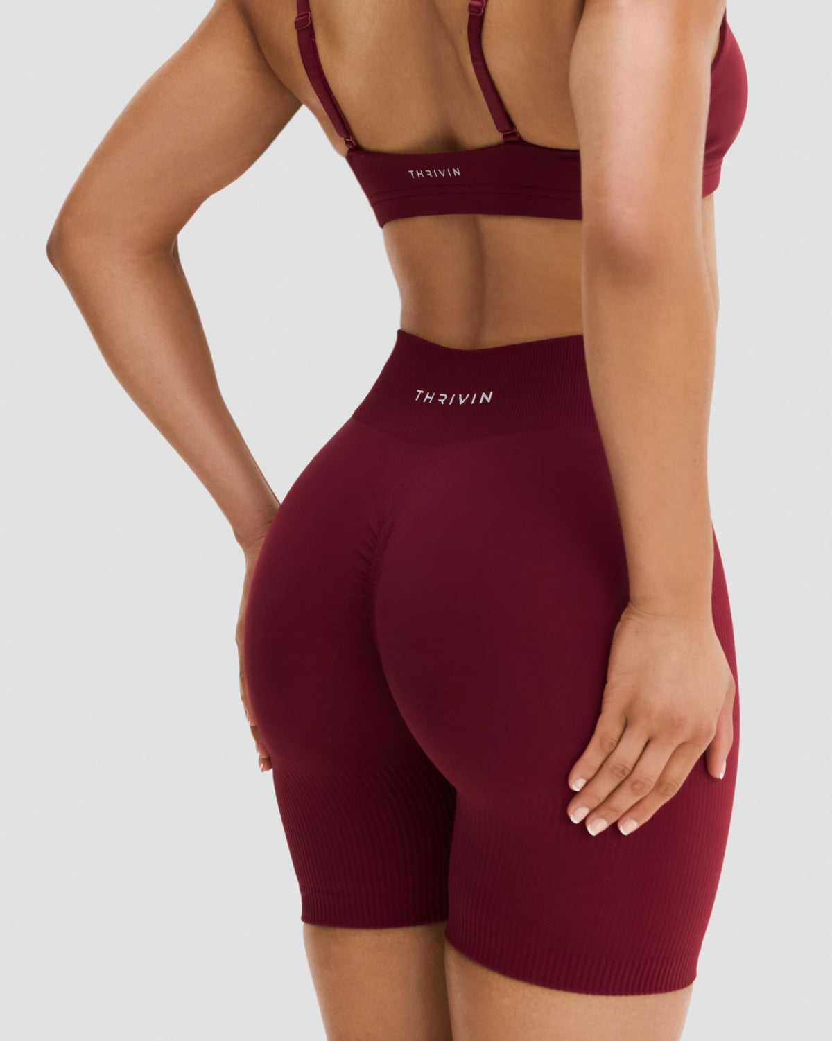 Elevate Sculpting Mid Waist Scrunch Shorts in Fine Wine Red, back close-up of THRIVIN logo, scrunch seam and ribbed leg hem