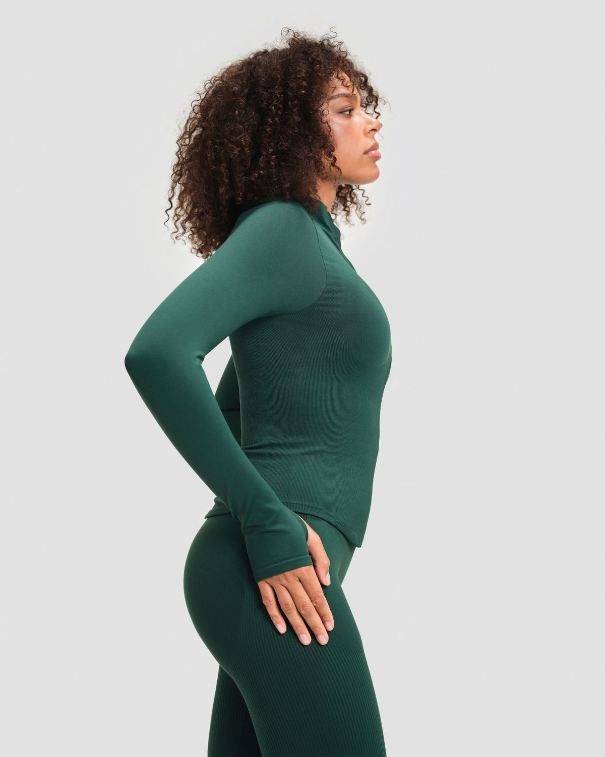 Elevate Compression Long Sleeve Jacket in Pine Green, side view of snug ribbed fit, curved hem and thumbholes