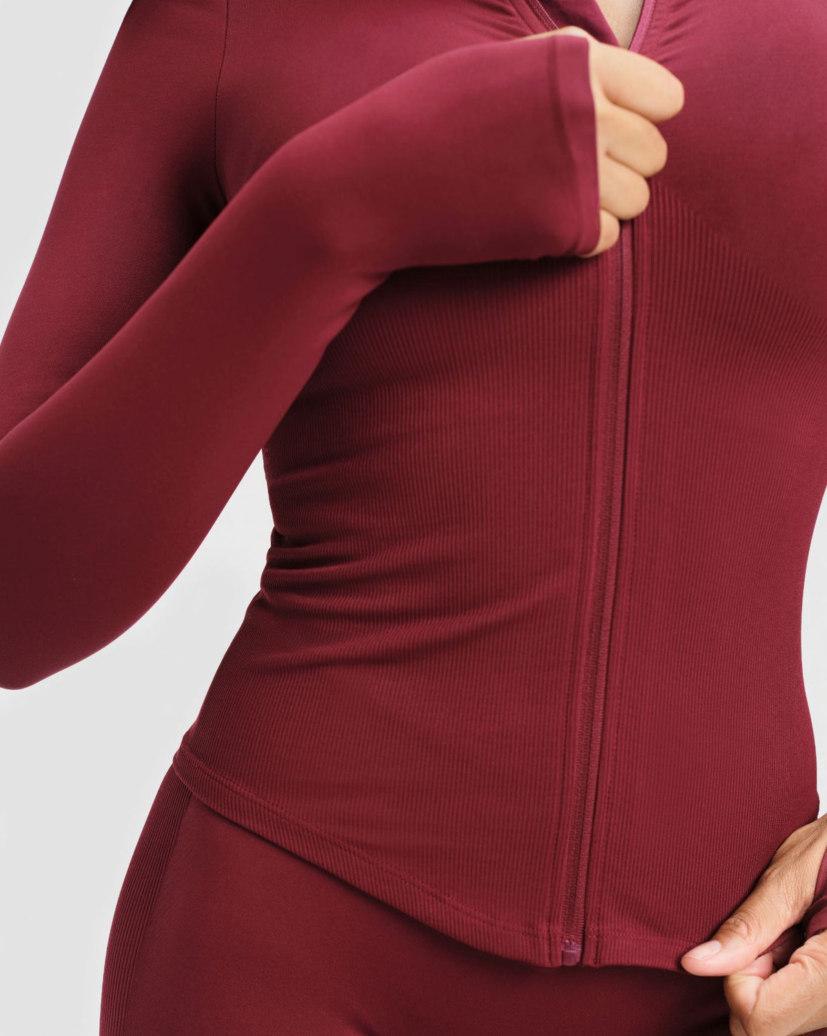 Elevate Compression Long Sleeve Jacket in Fine Wine Red, close-up of full-length front zip, thumbhole cuff and ribbed fabric