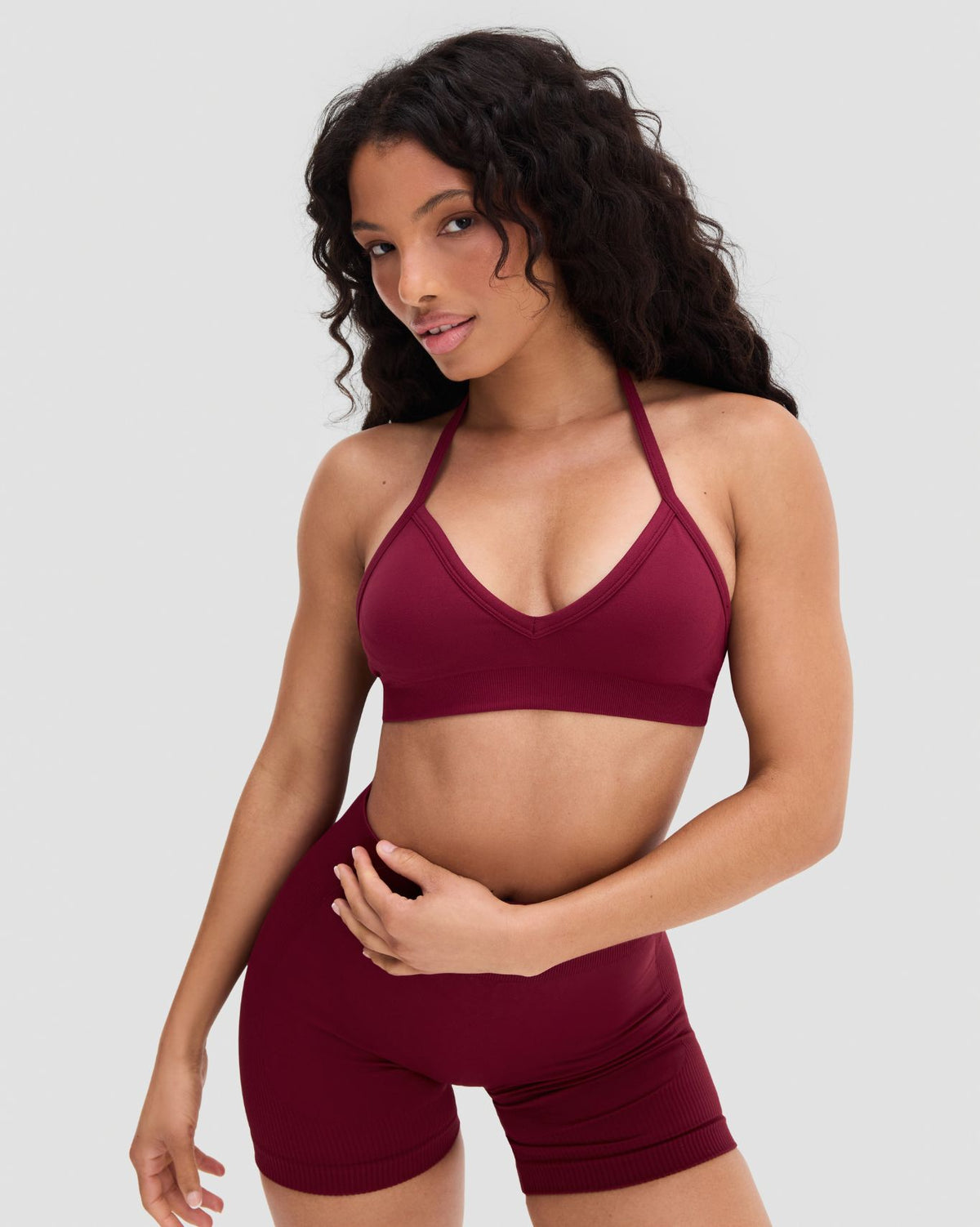 Elevate Sculpting Seamless Adjustable Halter Bra in Fine Wine Red, front view with hand on hip, styled with matching shorts