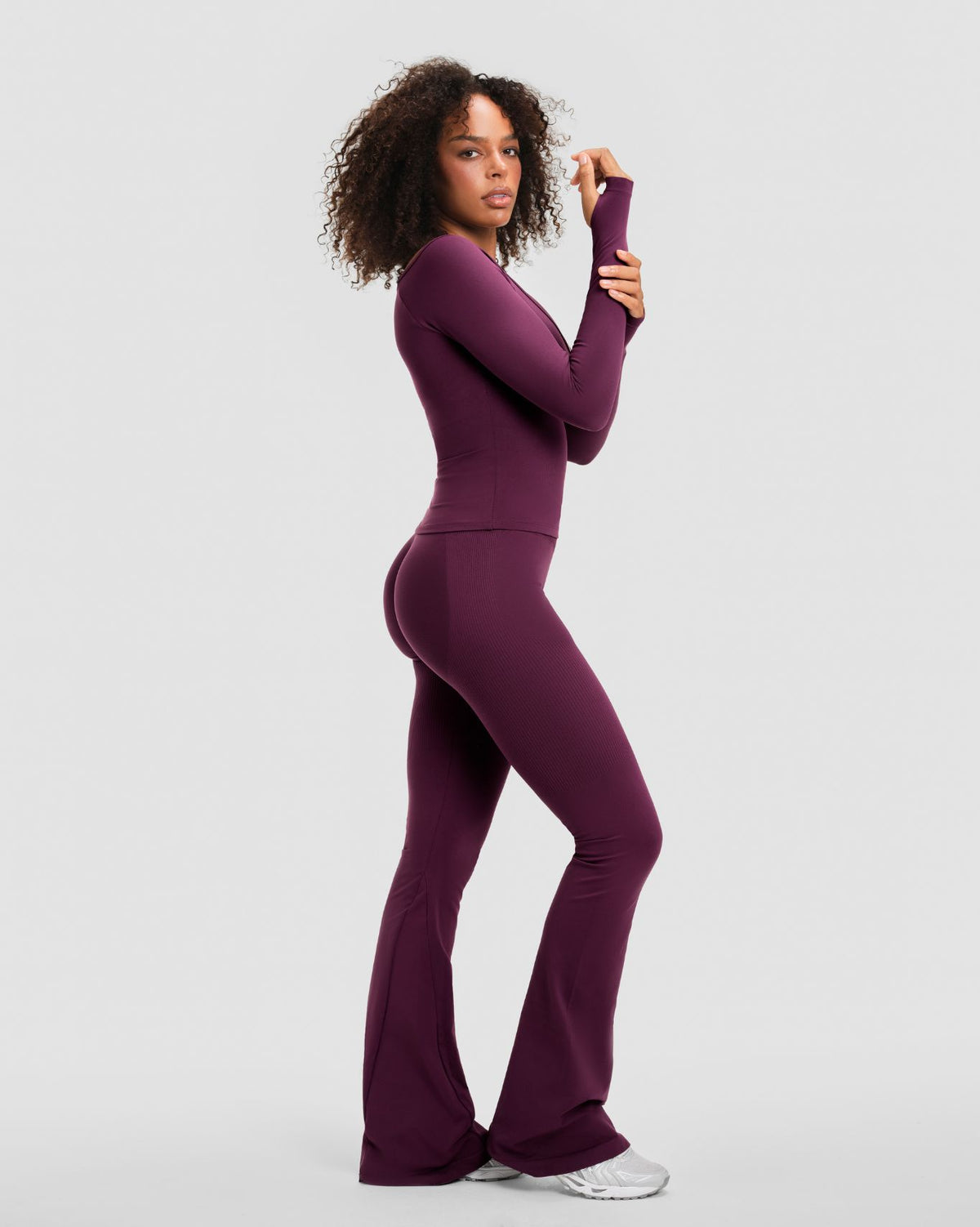 Elevate Sculpting Seamless V-Neck Top in Winter Plum Red, three-quarter back view with thumbholes and flare leggings