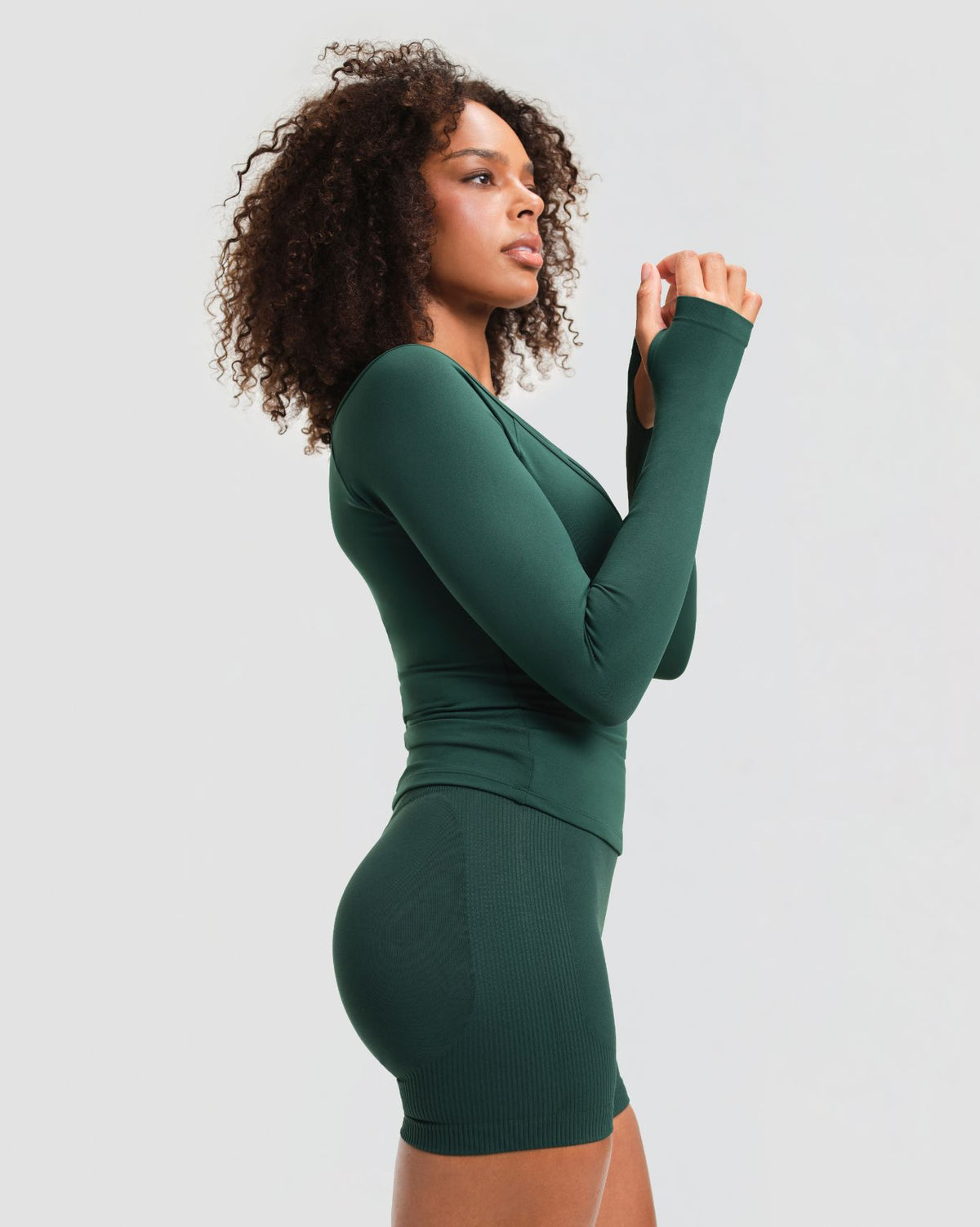 Elevate Sculpting Seamless V-Neck Top in Pine Green, side view of fitted sleeves, thumbhole cuffs and hip-length hem