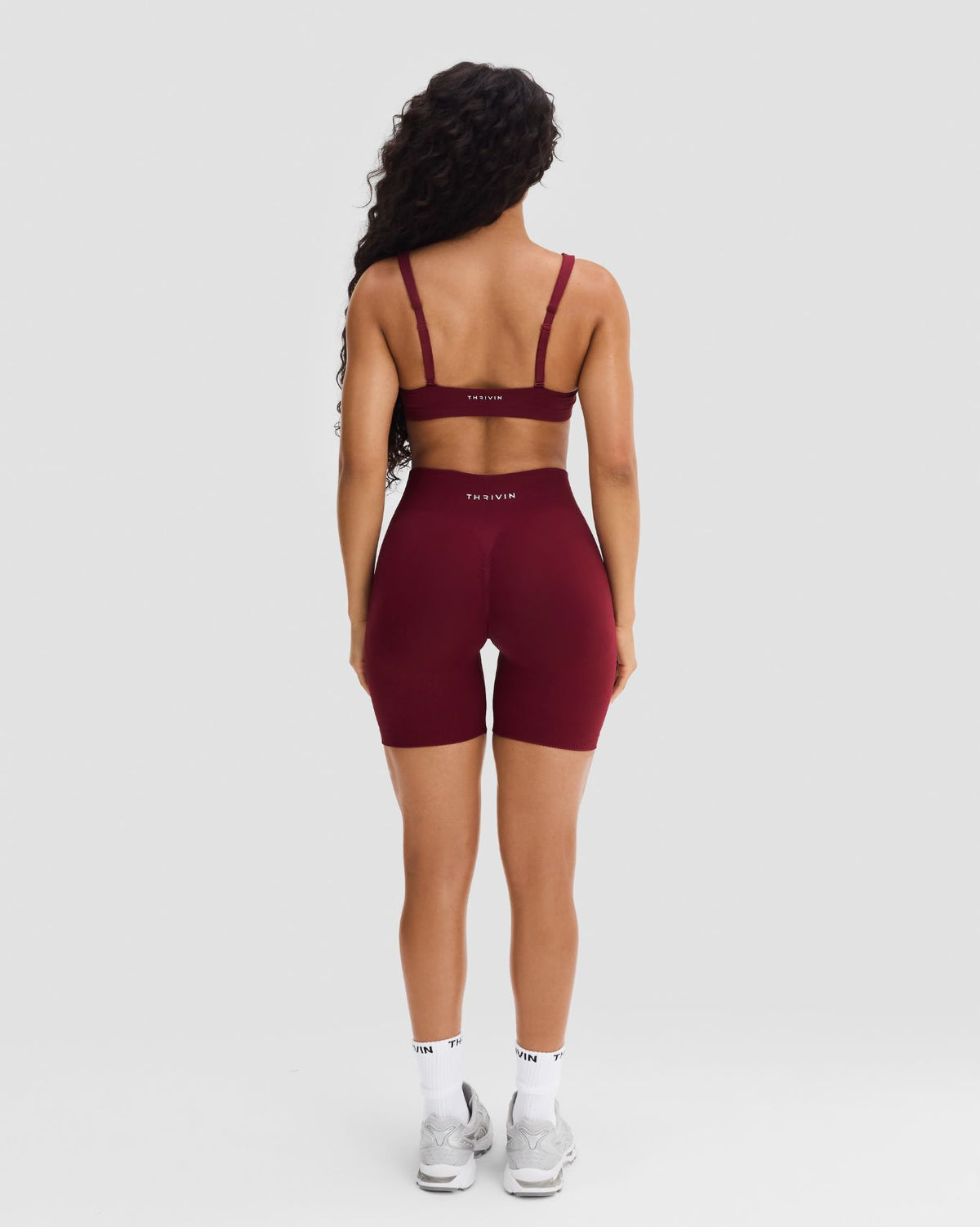 Elevate Sculpting Mid Waist Scrunch Shorts in Fine Wine Red, full-length back view of THRIVIN logo waistband and scrunch seam