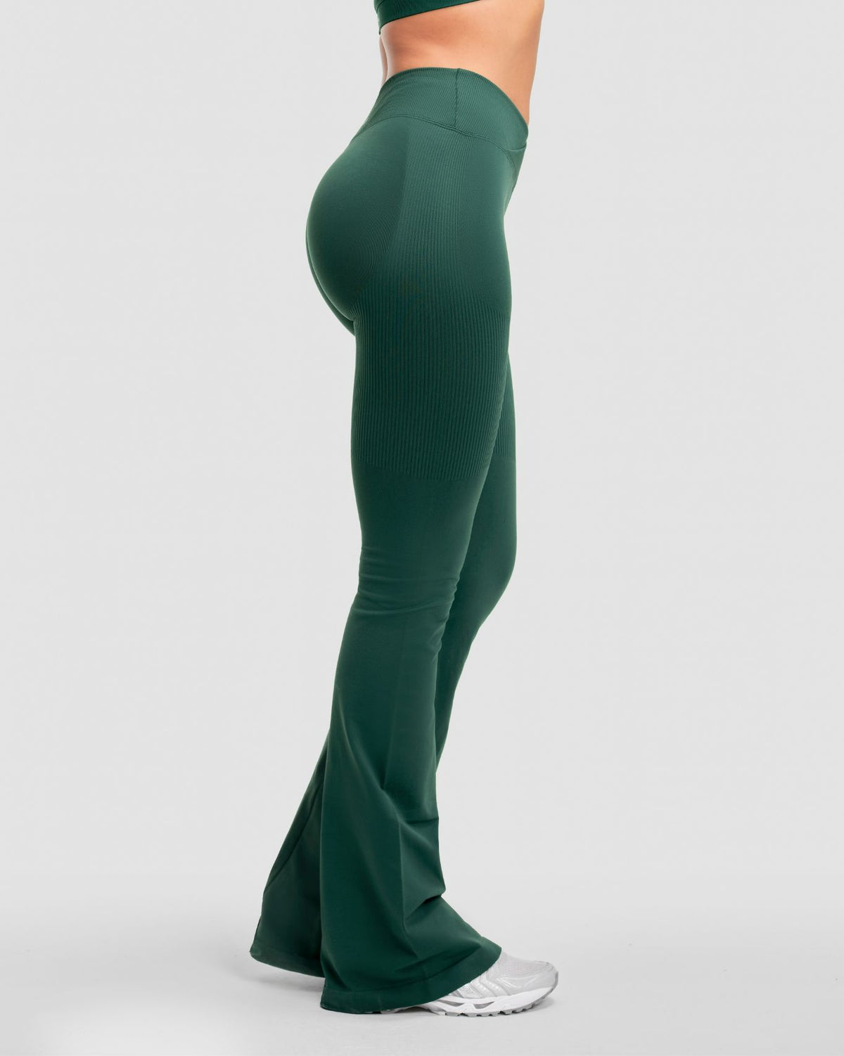 Elevate Sculpting Mid V-Waist Flare Leggings in Pine Green, side view from the waist down with flared hem