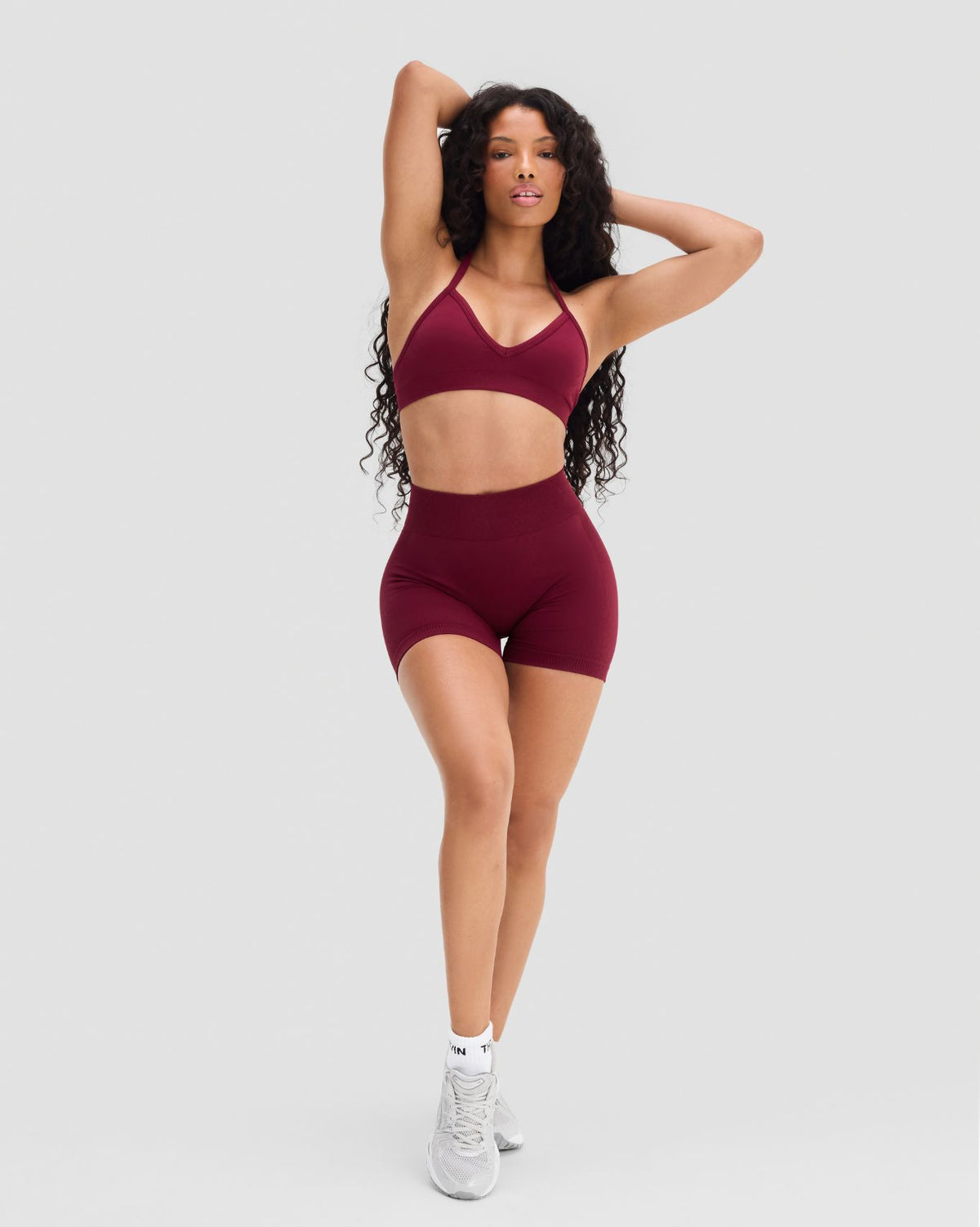 Elevate Sculpting Seamless Adjustable Halter Bra in Fine Wine Red, full-length front view with arms raised, with shorts